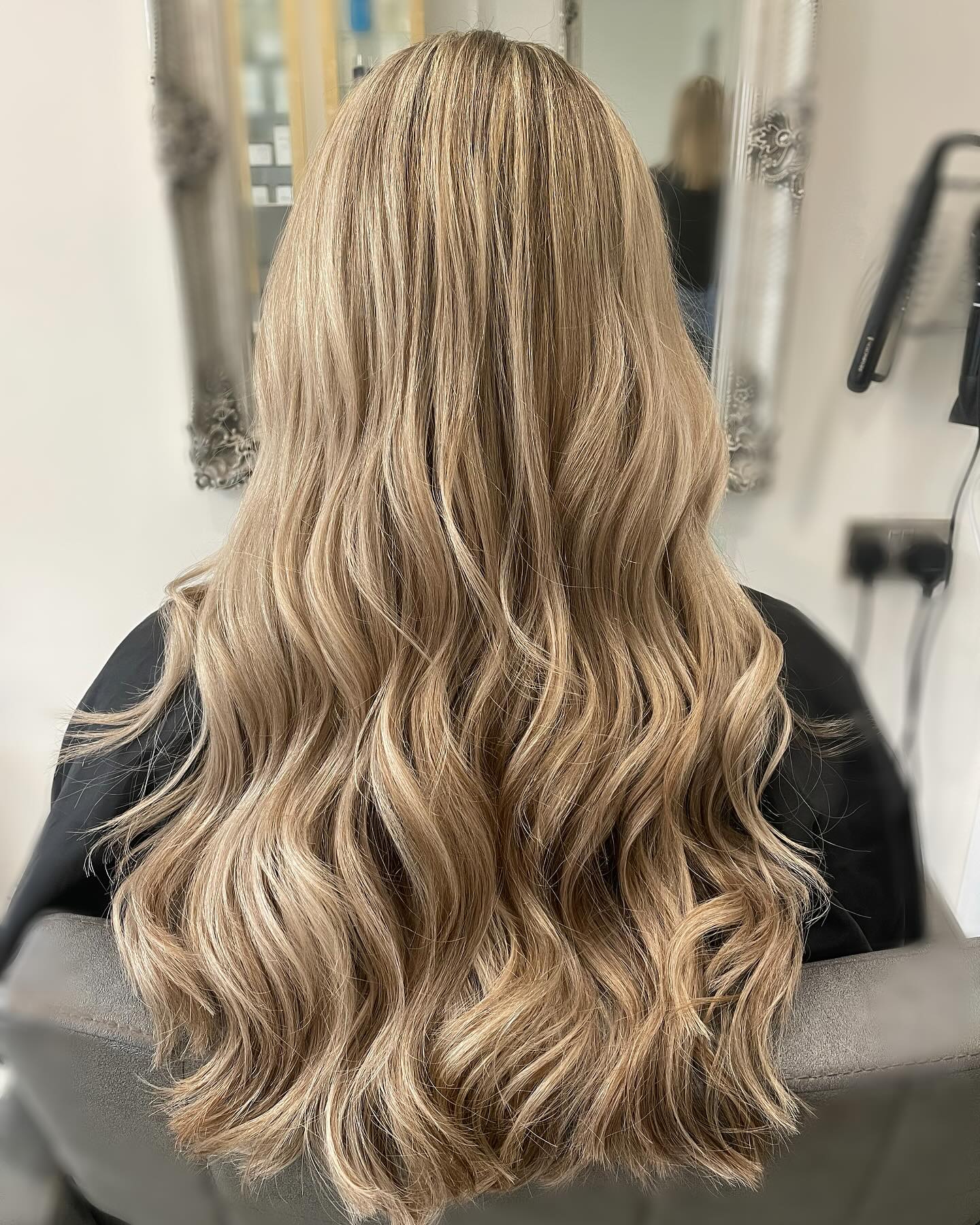 Beige blonde balayage on long hair with soft waves and dimensional colour.