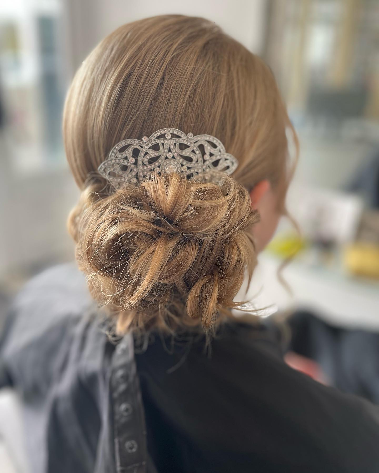 Elegant bridal low bun with a crystal hair comb accessory.