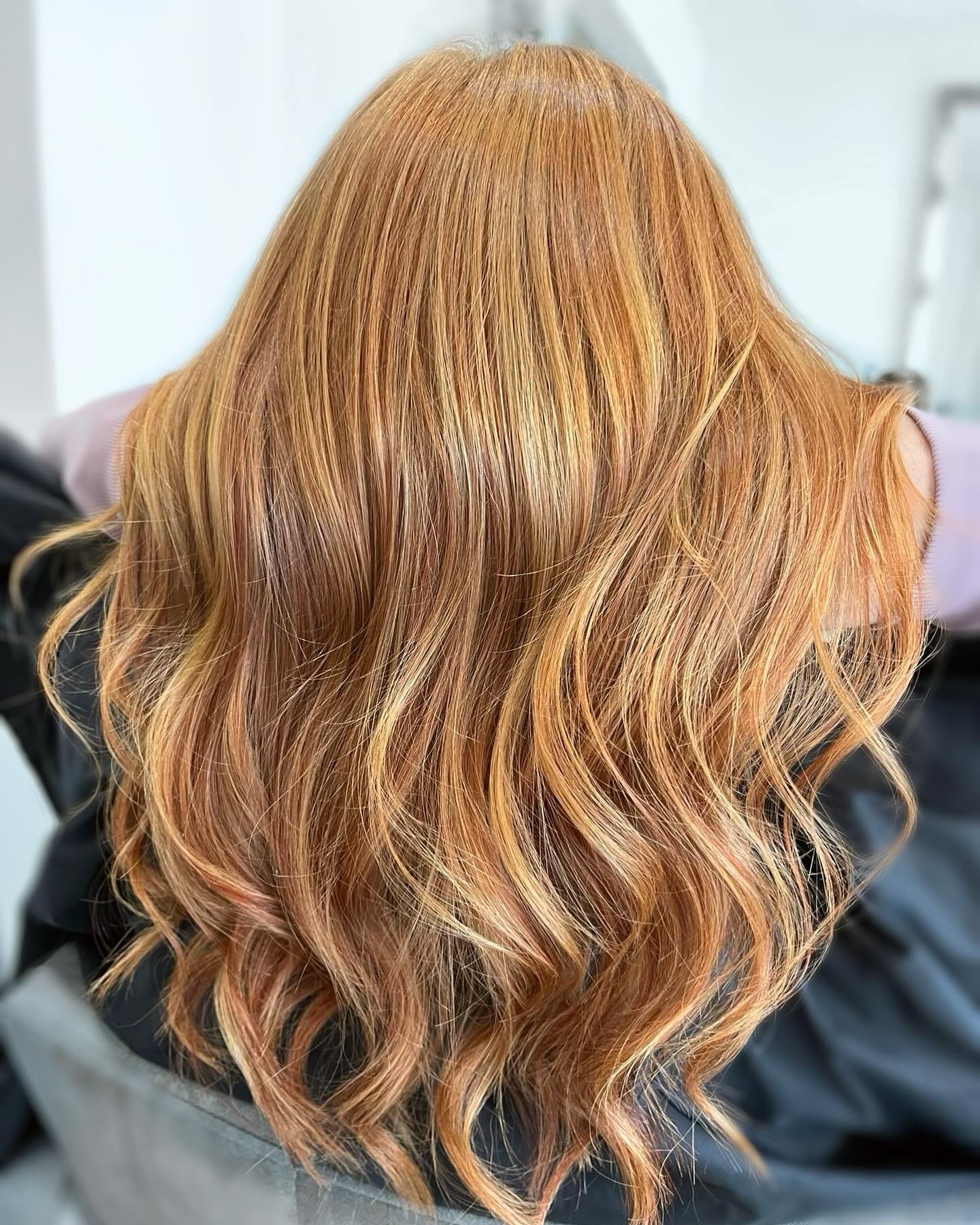 Copper blonde balayage with loose waves and warm tones.