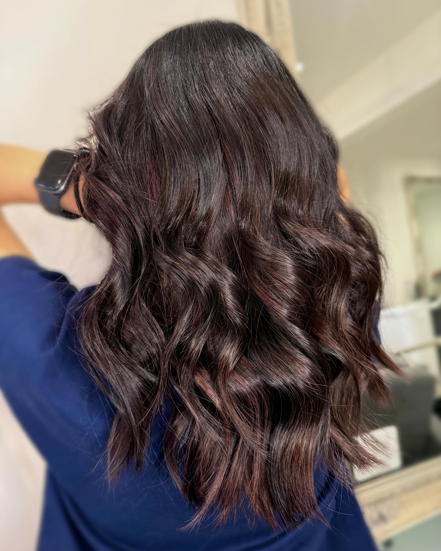 Dark chocolate brunette hair styled with glossy waves.