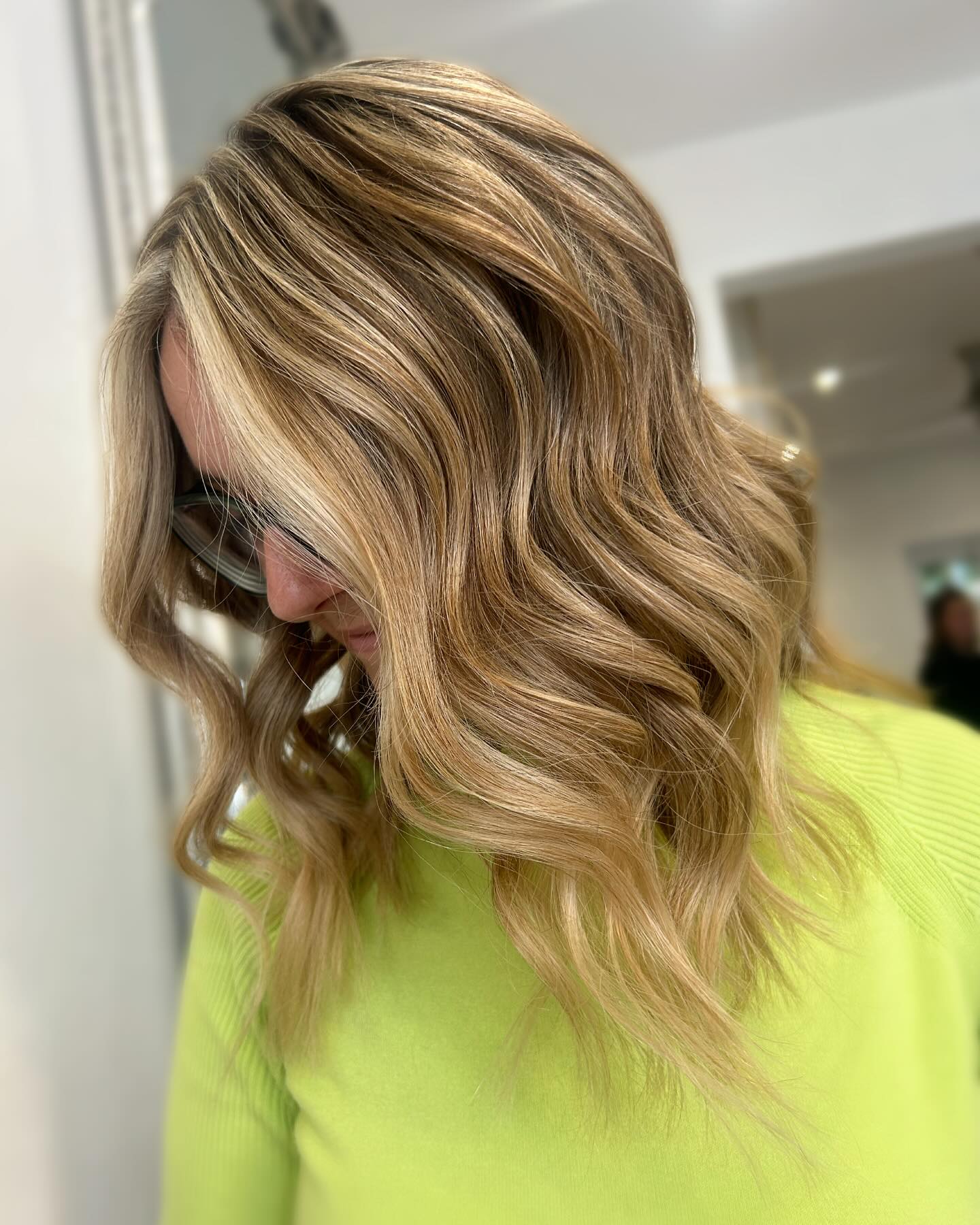 Honey blonde balayage with soft waves and warm dimension.