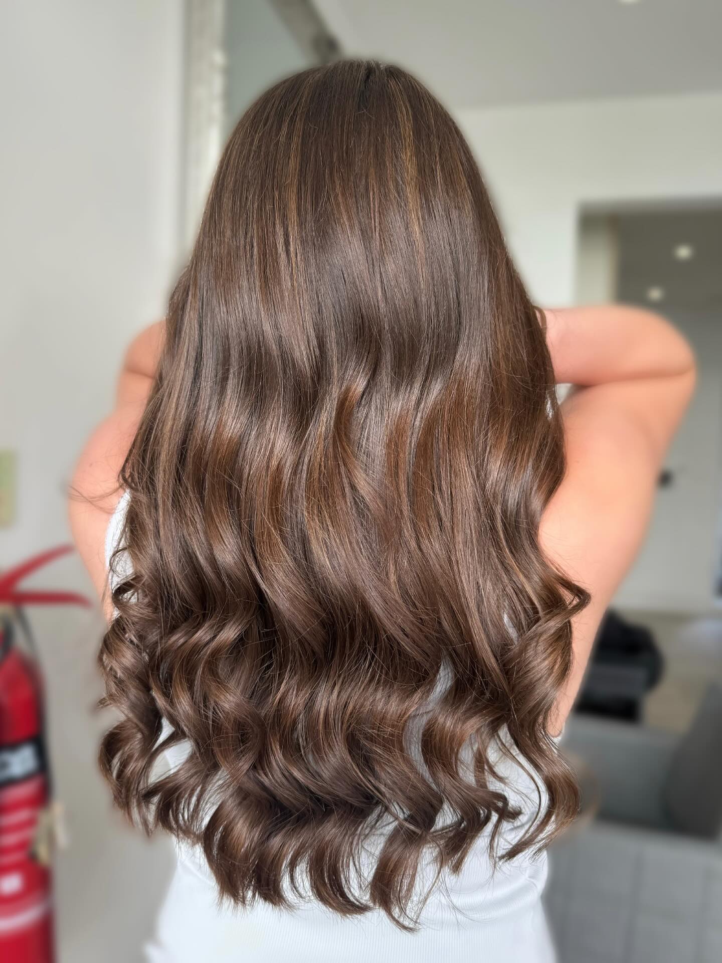 Rich chocolate brunette hair with soft glossy waves.