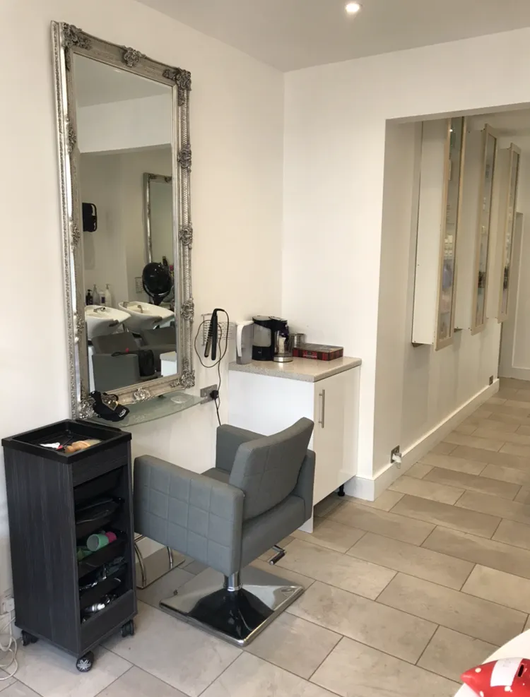 Hair styling station inside Hair Obsession with decorative mirror, styling chair and bright contemporary salon interior.
