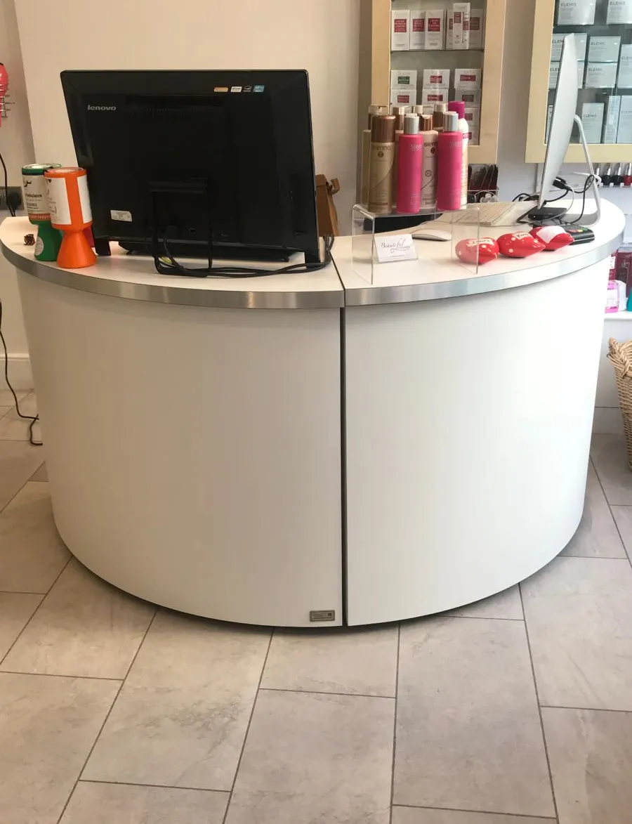 Curved reception desk at Hair Obsession salon with professional haircare products and customer service area.